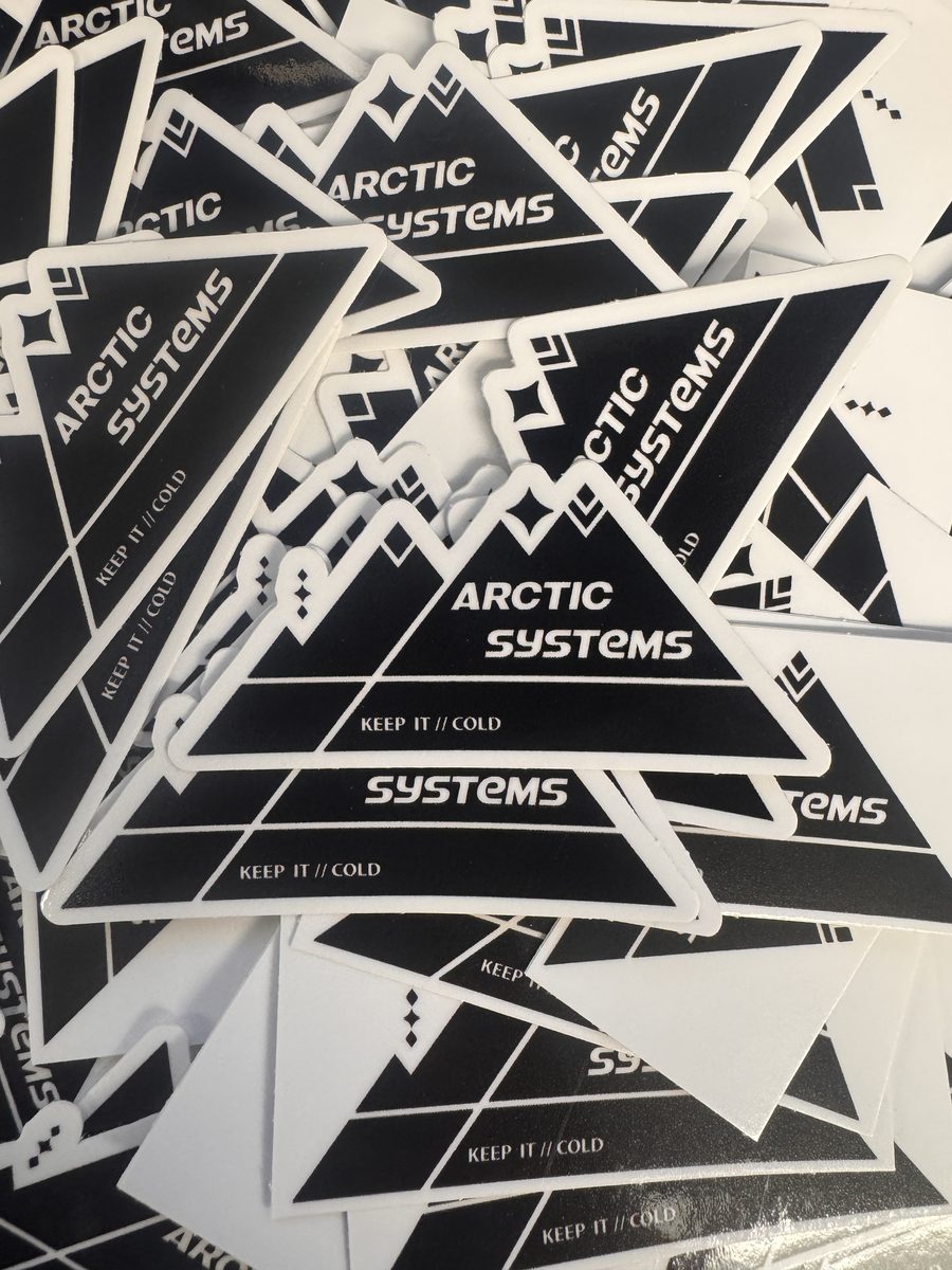 A stack of black and white Arctic Systems mountain-logo stickers